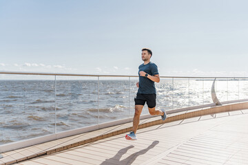 Motivation a male trainer does sports beautifully running. A happy athlete is a person. Using a smartwatch, a runner guy in fitness clothes looks at the time.