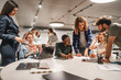 © qunica.com - Handsome male employee reading and discussing financial graph report with his multiracial colleagues at the office