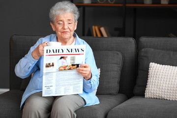 Poster - Senior woman with cup of coffee reading newspaper at home