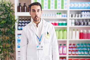 Poster - Handsome hispanic man working at pharmacy drugstore making fish face with lips, crazy and comical gesture. funny expression.