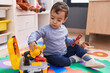© Krakenimages.com - Adorable hispanic boy playing with tools toy sitting on floor at kindergarten