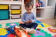 © Krakenimages.com - Adorable hispanic boy playing with car and dinosaur toy sitting on floor at kindergarten