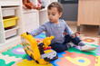 © Krakenimages.com - Adorable hispanic boy playing with tools toy sitting on floor at kindergarten