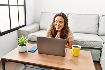 Wall Mural - Young beautiful hispanic woman having video call sitting on floor at home