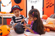 © Krakenimages.com - Adorable boy and girl having halloween party drawing on balloon at home