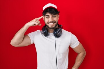 Poster - Hispanic man with beard wearing gamer hat and headphones smiling pointing to head with one finger, great idea or thought, good memory