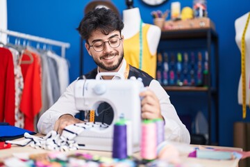 Canvas Print - Young hispanic man tailor smiling confident using sewing machine at sewing studio