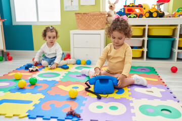 Poster - Adorable girls playing telephone toy sitting on floor at kindergarten