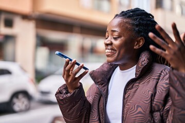 Wall Mural - African american woman smiling confident talking on the smartphone at street