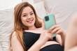 © Krakenimages.com - Young caucasian woman using smartphone lying on bed at bedroom