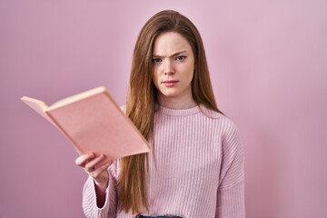 Sticker - Young caucasian woman reading a book over pink background skeptic and nervous, frowning upset because of problem. negative person.