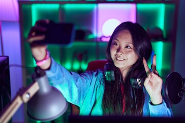 Poster - Young chinese woman streamer smiling confident make selfie by smartphone at gaming room