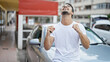 © Krakenimages.com - Young hispanic man holding key of new car doing thumb up gesture at street