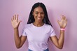 © Krakenimages.com - African american woman with braids standing over pink background showing and pointing up with fingers number ten while smiling confident and happy.