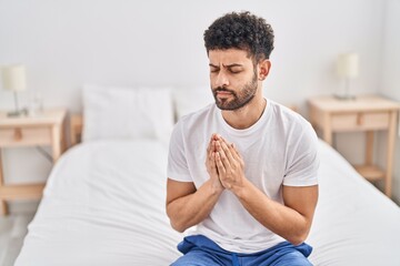 Sticker - Young arab man praying sitting on bed at bedroom