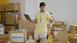 © Krakenimages.com - Young hispanic man volunteer using laptop checking products at charity center