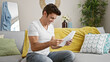 © Krakenimages.com - Young hispanic man reading document sitting on sofa at home