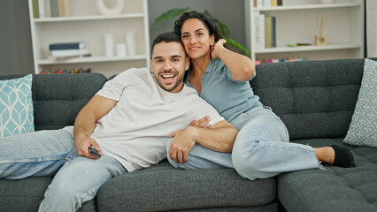 Poster - Man and woman couple hugging each other watching television at home