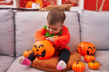 Adorable Hispanic Baby Having Halloween Party Wearing Pumpkin Costume At Home