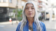 © Krakenimages.com - Middle age grey-haired woman standing with serious expression at street