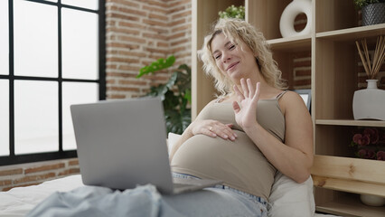 Poster - Young pregnant woman having video call touching belly at bedroom