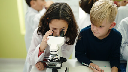 Sticker - Adorable boy and girl students using microscope writing notes at laboratory classroom