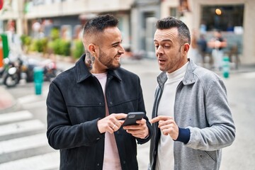 Canvas Print - Two men couple smiling confident using smartphone at street