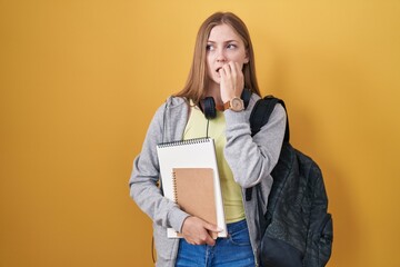 Canvas Print - Young caucasian woman wearing student backpack and holding books looking stressed and nervous with hands on mouth biting nails. anxiety problem.