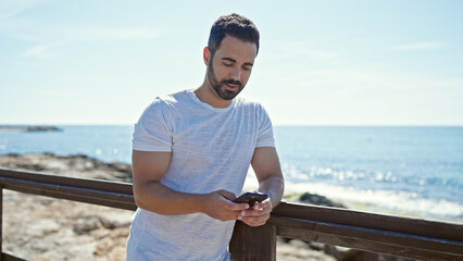 Sticker - Young hispanic man using smartphone at seaside