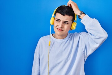 Canvas Print - Non binary person listening to music using headphones confuse and wondering about question. uncertain with doubt, thinking with hand on head. pensive concept.