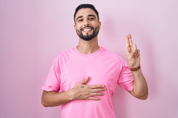 Canvas Print - Hispanic young man standing over pink background smiling swearing with hand on chest and fingers up, making a loyalty promise oath