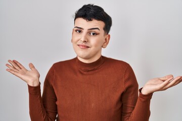 Sticker - Non binary person wearing make up standing over isolated background clueless and confused expression with arms and hands raised. doubt concept.