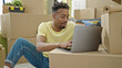 © Krakenimages.com - African american man using laptop sitting on floor at new home