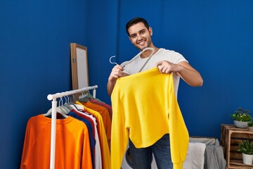 Wall Mural - Young hispanic man putting clothes on clothes rack at laundry room