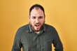 © Krakenimages.com - Plus size hispanic man with beard standing over yellow background afraid and shocked with surprise and amazed expression, fear and excited face.