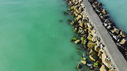 Canvas Print - Aerial of the rocky pier surrounded by the blue waters of the calm sea during the daytime