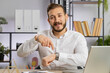 © Andrii Iemelianenko - It is your time. Young middle eastern boss business man showing time on wrist watch clock, approve, pointing finger, time to start work, deadline. Freelancer guy at office workplace looking at camera