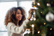  Beautiful young woman decorating a Christmas tree