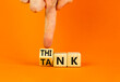 Think tank symbol. Businessman turns wooden cubes and changes the word Tank to Think or vice versa. Beautiful orange table orange background, copy space. Business, think tank concept.