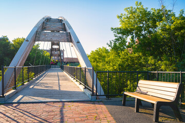 Wall Mural - Gateway Crossing pedestrian bridge and a wooden bench over the Meduxnekeag River park in Aroostook County, Maine