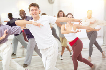 Wall Mural - Happy caucasian man learning new modern dance in group dance lesson