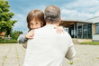 © Elena Medoks - Satisfied son hugging his dad next to the school building after the end of the lessons.