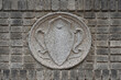 a molded concrete medallion in the art noveau style in neutral beige tones inset on a wall of beige gray bricks