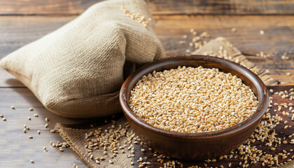 Wall Mural - Buckwheat groats (hulled seeds) in bowl and burlap bag. Ingredient in breakfast food. Buckwheat whole grains on wooden table, selective focus