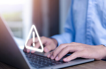 Wall Mural - businessman using laptop showing warning triangle and exclamation sign icon warning of dangerous pro