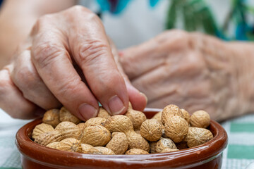 Wall Mural -  Close-up, a person picks peanuts from a ceramic plate.j