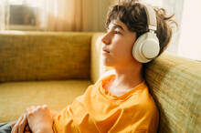 Thoughtful Boy With Headphones Relaxing On Sofa