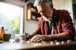 © fotogurme - American man in red shirt pouring pills from prescription pill bottle