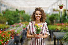 Smiling Woman Holding Flowering Plant At Nursery