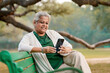 © Niks Ads - Indian senior woman using smartphone at park.
